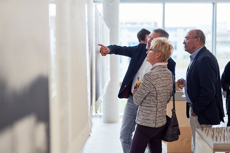 People standing at a table and talking at the work exhibition/graduation ceremony at the Faculty of Architecture