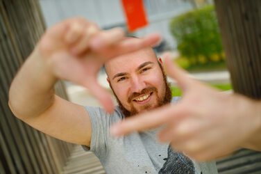 Photo of a student forming a square with his index fingers and thumb in front of him and looking through it.