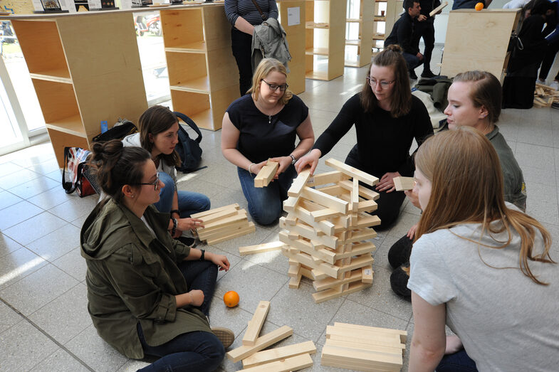 Visitors to the Open Day at the Faculty of Architecture build a tower out of wooden blocks