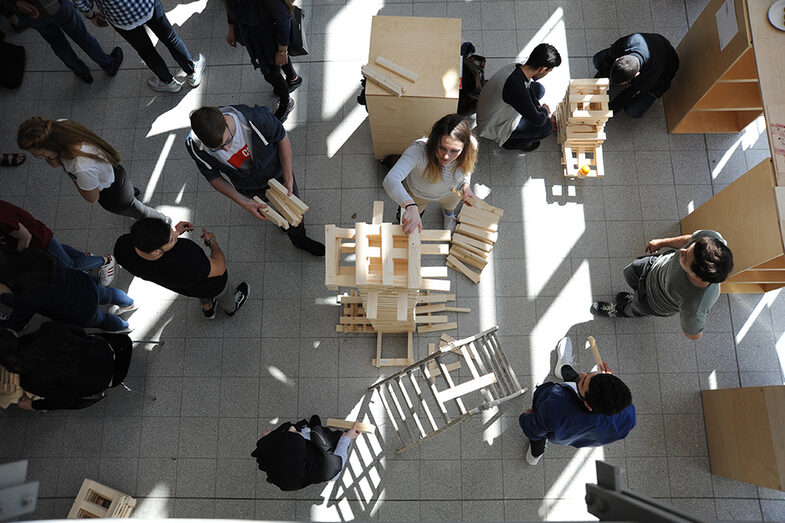 Visitors to the Open Day at the Faculty of Architecture build a tower out of wooden blocks