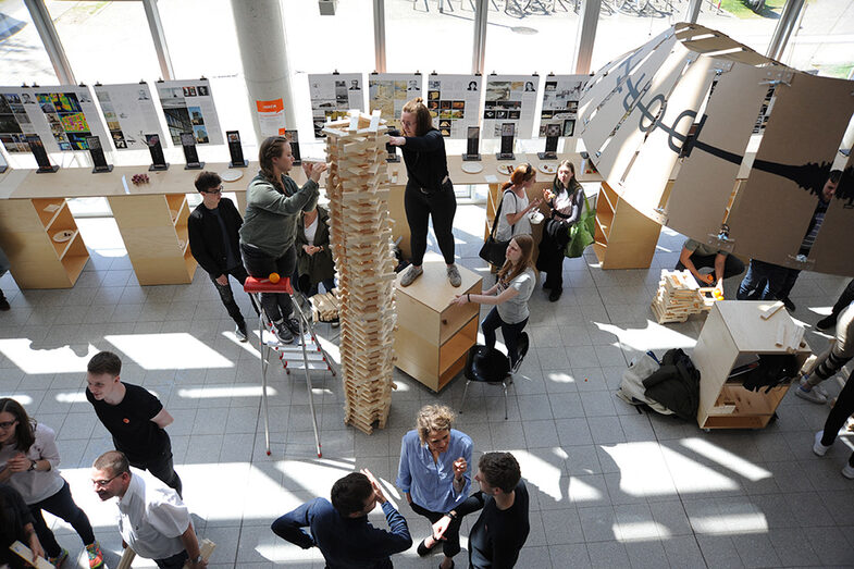 Visitors to the Open Day at the Faculty of Architecture build a tower out of wooden blocks