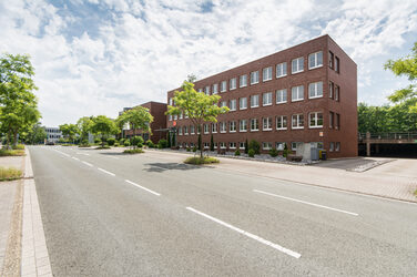 Photo of Otto-Hahn-Straße with several buildings of Fachhochschule Dortmund and trees along the street.