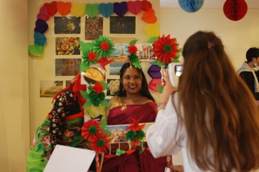 A student takes a photo of another student standing behind a colorfully decorated frame.
