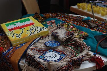 Cultural stand Iran: Colorful cloths on a table, next to painted canvases with characters.