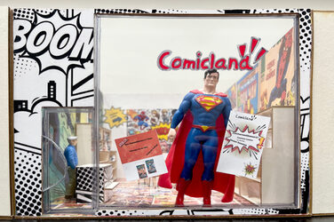 Eine Supermanfigur steht im Schaufenster eines Miniaturmodells eines Comicladens.