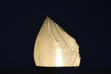 Night shot of a model of a shell-like curved luminaire with generatively manufactured lampshade in beige