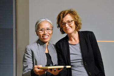 Prof. Christine Remensperger überreicht der Gast-Professorin aus Bali ein Geschenk als Dankeschön für ihren Vortrag im Hörsaal des Fachbereichs.