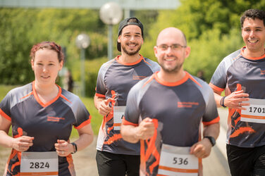 Photo of four employees in FH running gear taking part in an organized run. __ Employees with FH equipment take part in an organized run.