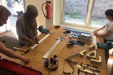 Students work together on their banisters on a workbench in the metal lab.