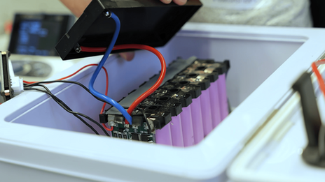 Blick auf einen Batteriespeicher mit mehreren Zellen plus Elektronik in einer Sicherheitsbox mit offenem Deckel.
