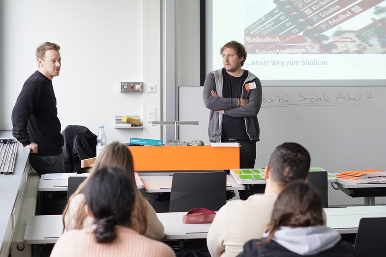Two students stand in front of a class and give a presentation at the Social Work Taster Day.