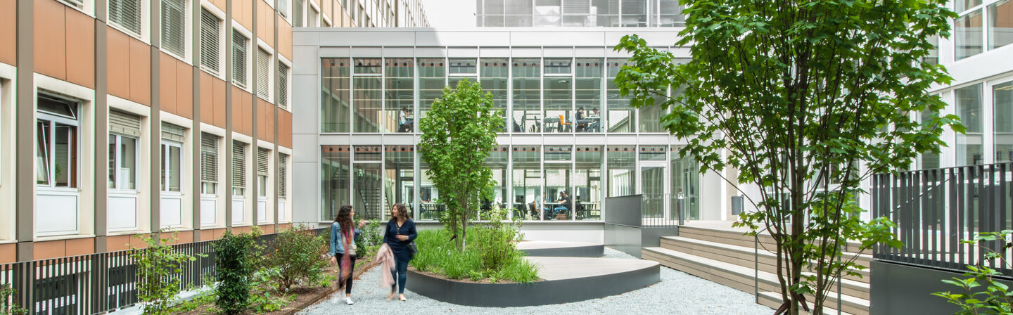 Photo of the inner courtyard at the student workplaces on Sonnenstraße. Two women are walking in the courtyard.