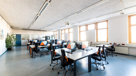 Room shot of the laboratory for networks and operating systems, with several rows or groups of tables equipped with computers.