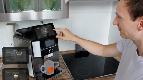 Smart coffee machine as a household assistant operated by a young man.