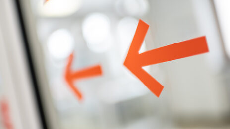 Photo of two orange arrows on a glass door.