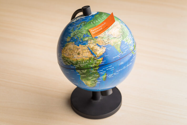 Photo of a globe with a note with the FH word mark stuck to it.