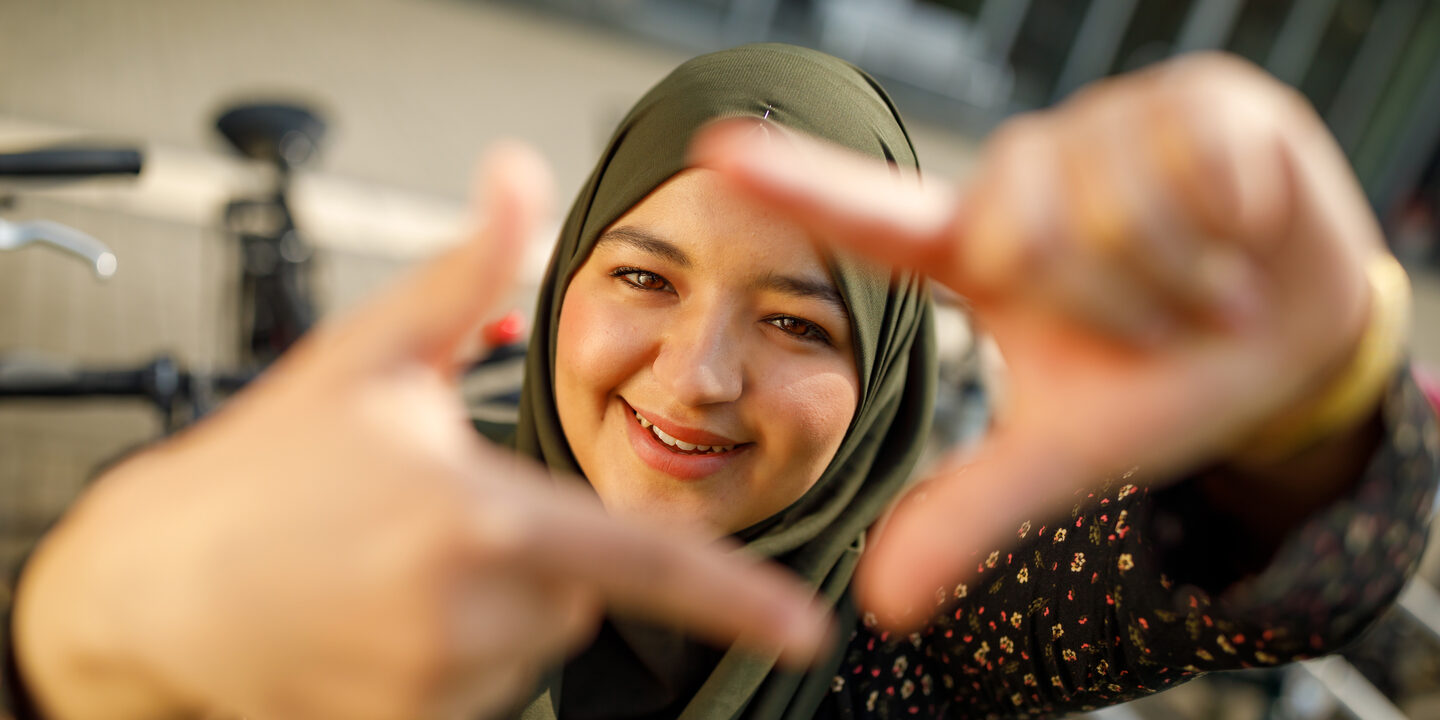 Photo of a student forming a square with her index fingers and thumb in front of her and looking through it.