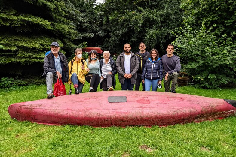 Participants in the senior sponsorship program at the end of a canoe trip. The canoe lies in front of them. Behind them are 3 seniors and 5 international students__Participants of the senior mentoring program at the end of a canoe trip. The canoe lies in front of them. Behind it there are 3 senior students and 5 international students.