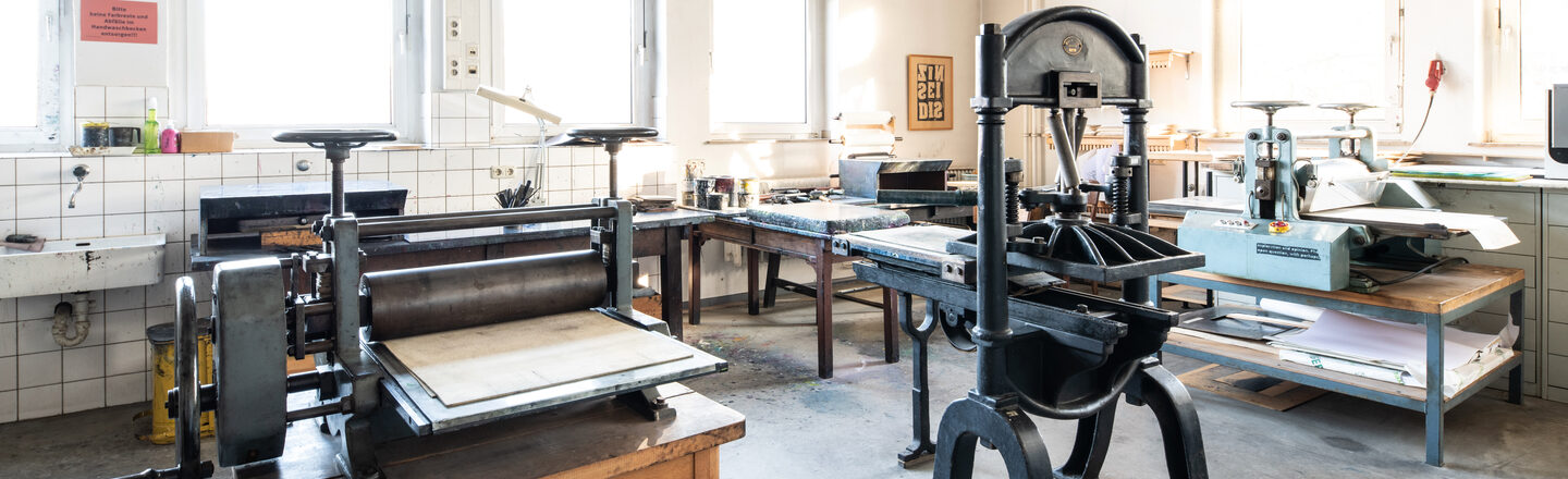 Photograph of the printing workshop with various large presses and printing equipment.