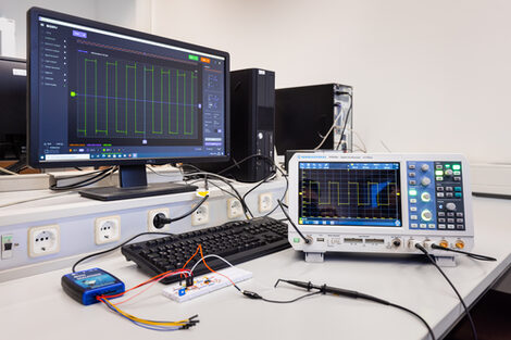 Photo of a set-up with plug-in boards for the electronic circuit and measuring devices as well as details of the measurement on the computer.