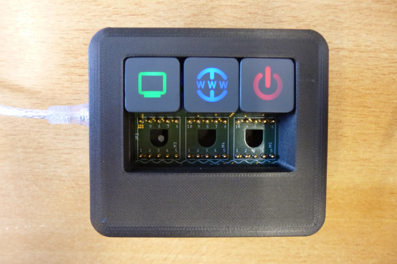 Photo of a freely configurable control element with three buttons and symbols that light up in different colors.
