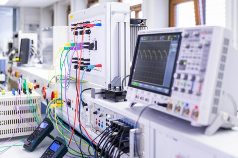 Photo from the laboratory for power electronics and drive systems. You can see various measuring devices and computers with lots of colored cables.