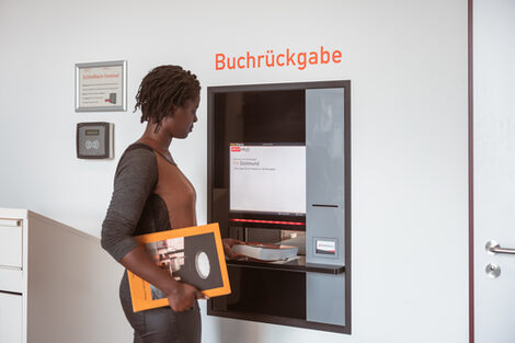 Photo of a student returning a book via the library's return machine.