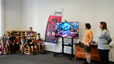 Sieben Schüler im linken Bildbereich hören Sabine Sachweh und Marcel Mitas bei der Beschreibung des Escape Rooms „Digitale Rettung“ zu.