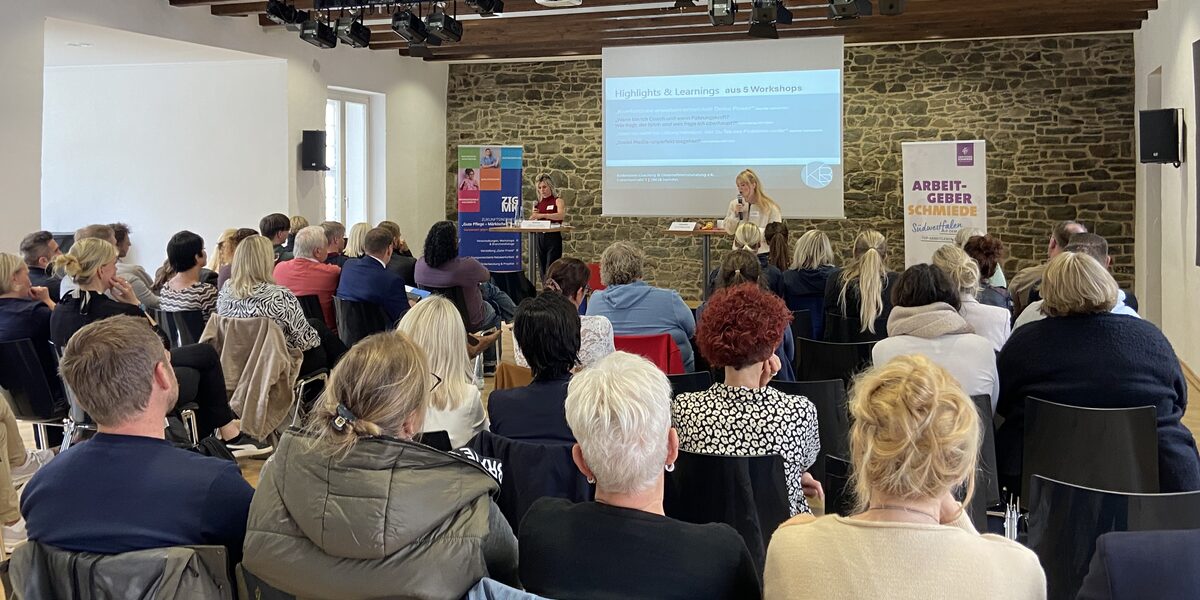 An einem Tisch stehend präsentieren Ansgar Rahmacher, Marcel Mitas und Leon Sachweh Assistenzsystem für die Gesundheits- und Pflegebranche.