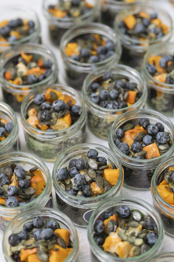 The picture shows a section of a buffet on which only glasses are lined up. In the glasses is a colorful salad.