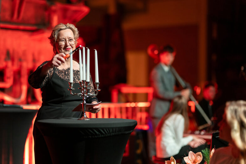Eine Person zündet Kerzen an einem Kerzenständer an.