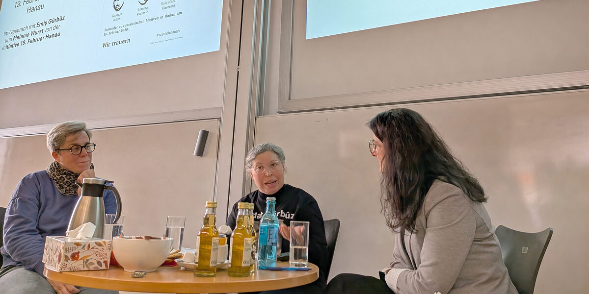 People talking to each other in front of a screen in a lecture hall.