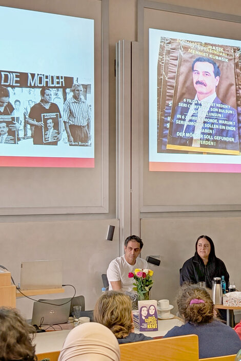 People talking to each other in front of a screen in a lecture hall.