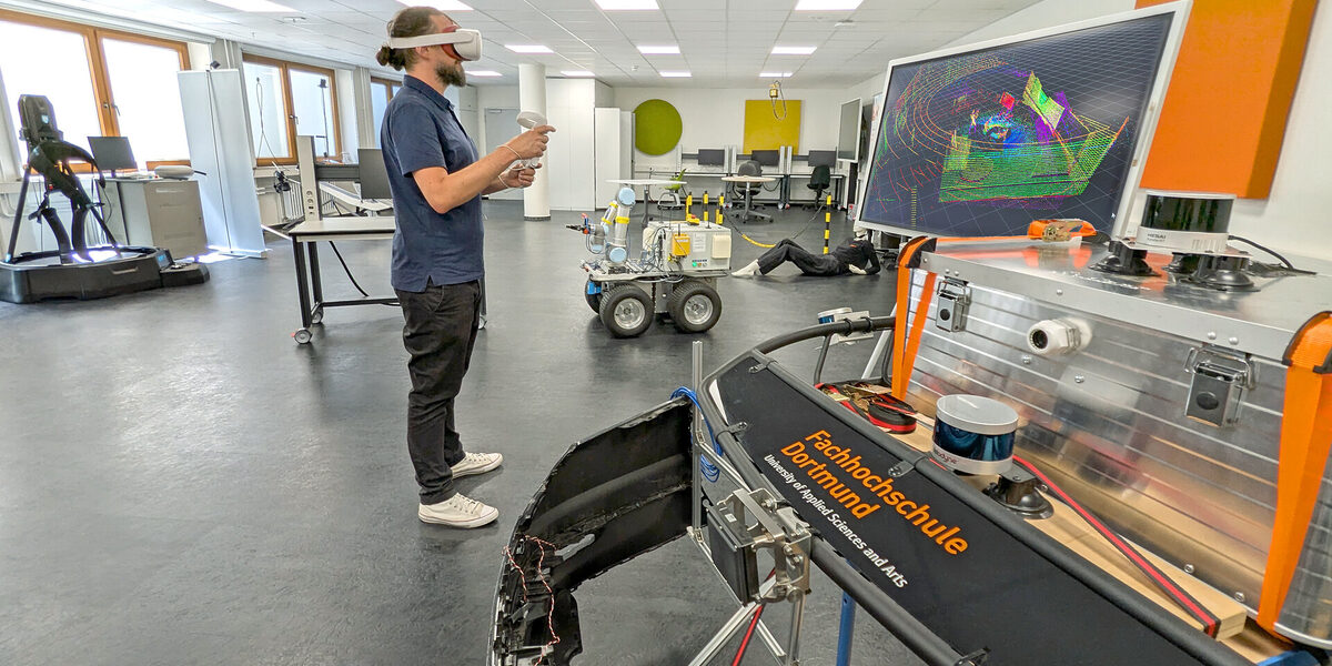 Eine Person mit einer VR-Brille steht in einem Labor. Vor ihr ein Monitor mit bunten Linien.