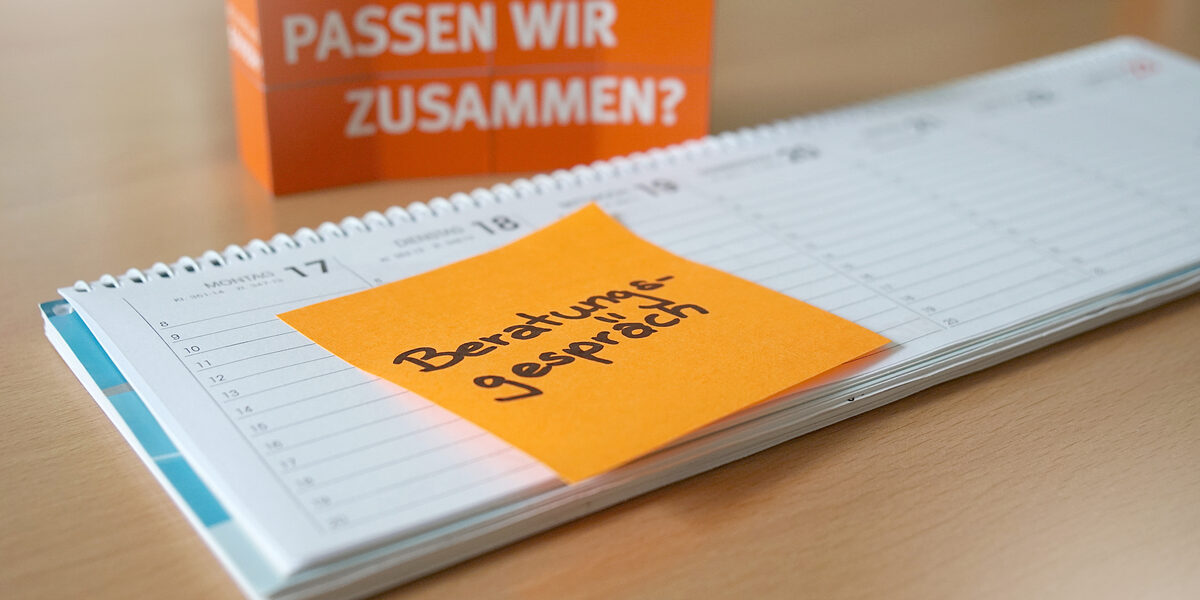 Photo of a desk calendar with an orange Post-It with the note "Counseling interview" stuck to it. In the background are stacked cubes with the words "Are we a match?" written on them.