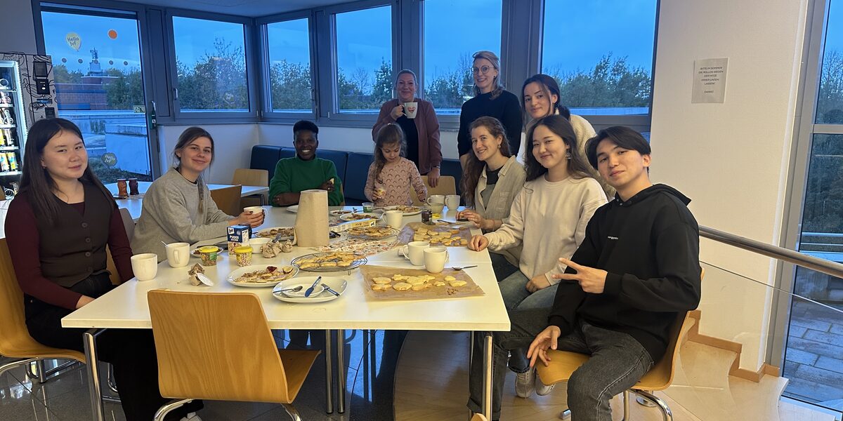 Several people are sitting at a table with cookies and coffee.