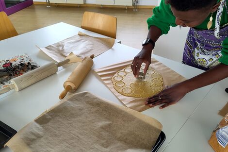 One person cuts out star-shaped cookies from dough.
