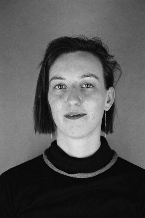 Schwarz-Weiß-Porträt einer Person mit kinnlangem Haar und dunklem Oberteil.