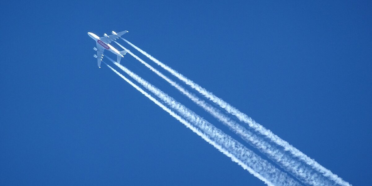 Am Himmel sind ein Flugzeug und dessen Kondensstreifen zu sehen.