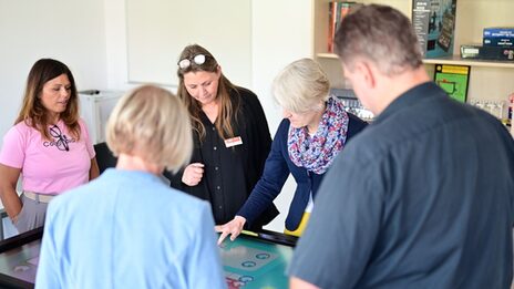 Several people are standing around a table whose surface is a touchscreen.