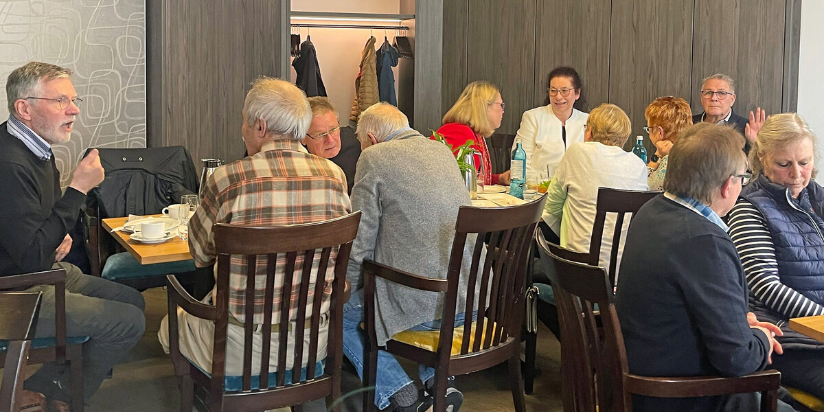 Menschen sitzen an Tischen und unterhalten sich.