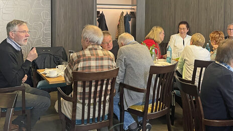 Menschen sitzen an Tischen und unterhalten sich.