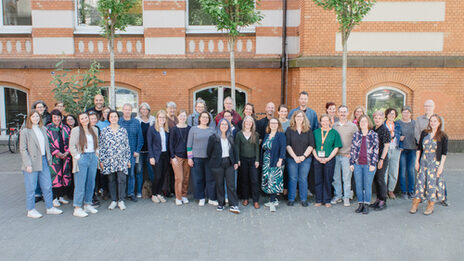 Participants of the "BAG Prax" conference stand in a group picture in the inner courtyard of Sonnenstraße