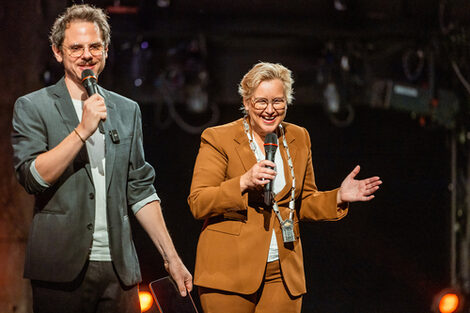 Two people with a microphone in their hands. They are obviously in a good mood.