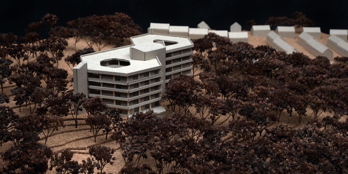 The photo shows the central model building surrounded by dense model trees, with other buildings in the background. The topography is represented by fine layers.