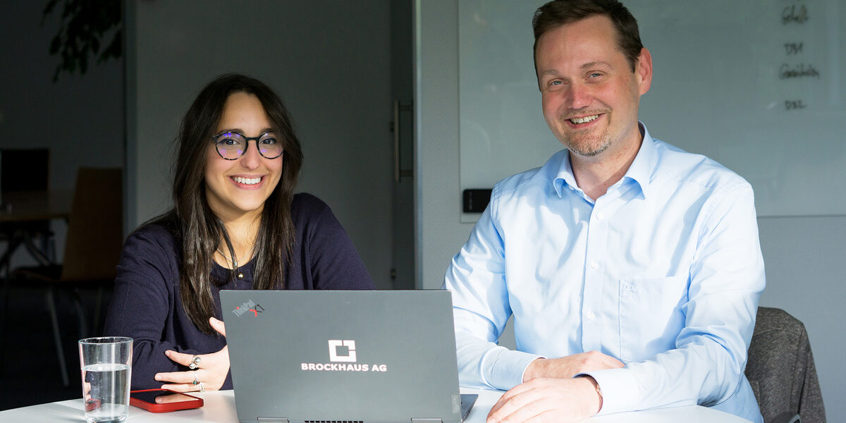 Zwei Personen sind zusammen vor einem Monitor und analysieren die Daten auf dem Bildschirm.