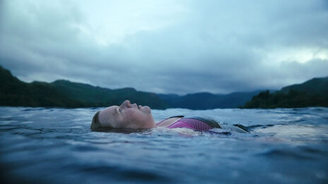 A woman swims with her back in a large body of water.