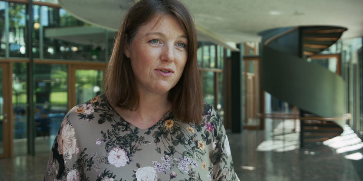 A female read person in an interview situation in front of the camera.