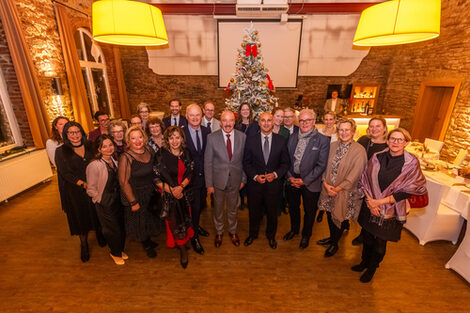 Eine Gruppe Menschen steht für ein gemeinsames Foto einen einem festlich dekorierten Saal.