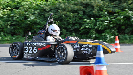A racing car from Fachhochschule Dortmund drives on a race track.